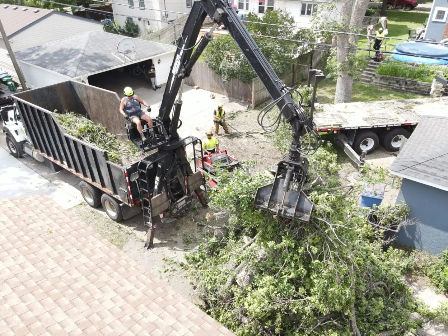 A log loader and grapple clearing brush and logs on a Twin Cities lot